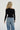 Person wearing a black off-shoulder top and light blue jeans on a white background